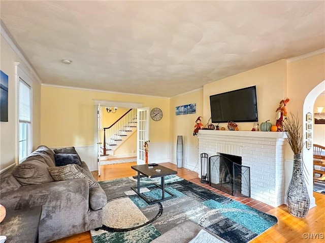 living room featuring ornamental molding, wood-type flooring, and a fireplace