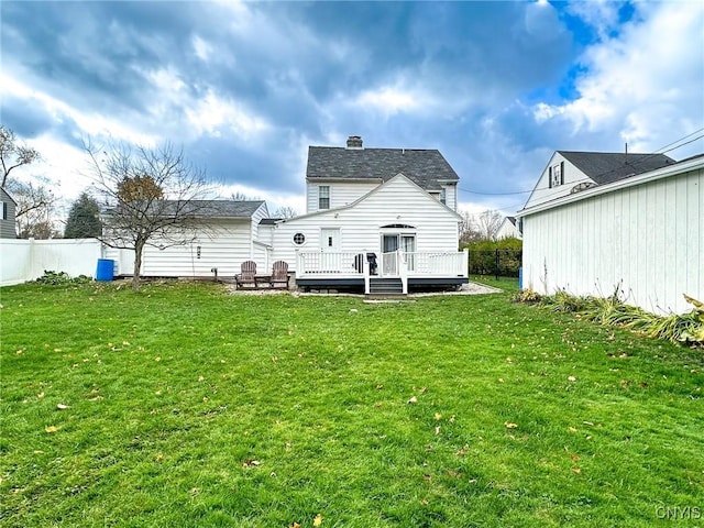 rear view of property featuring a wooden deck and a lawn