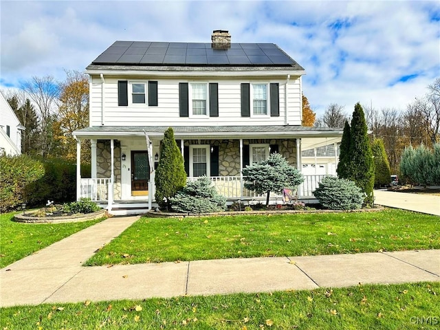 view of front of house with a porch, a front yard, and solar panels