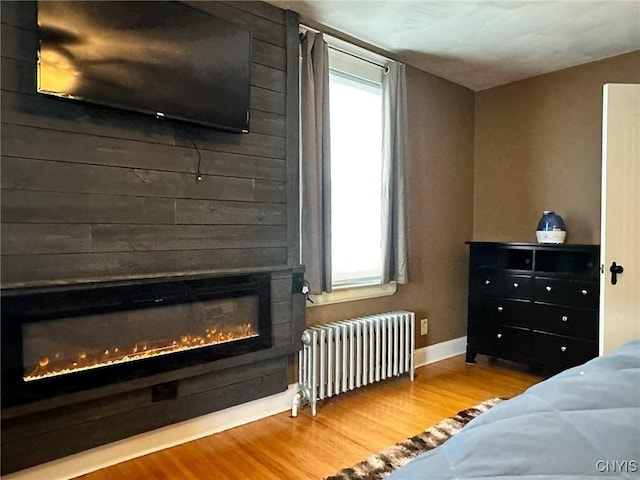 bedroom featuring a fireplace, radiator, and hardwood / wood-style floors