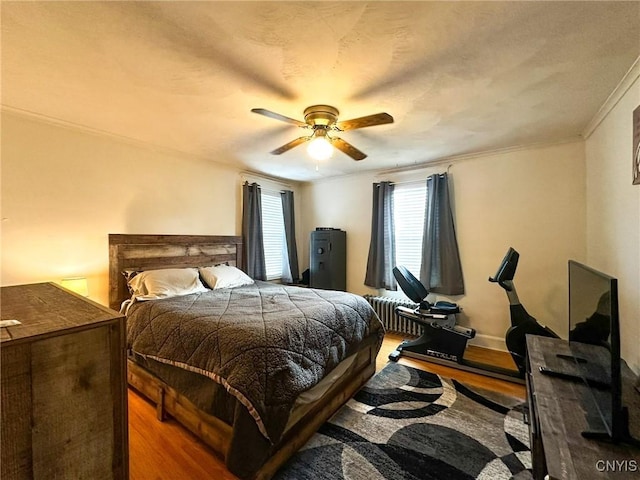 bedroom featuring wood-type flooring, ornamental molding, and ceiling fan