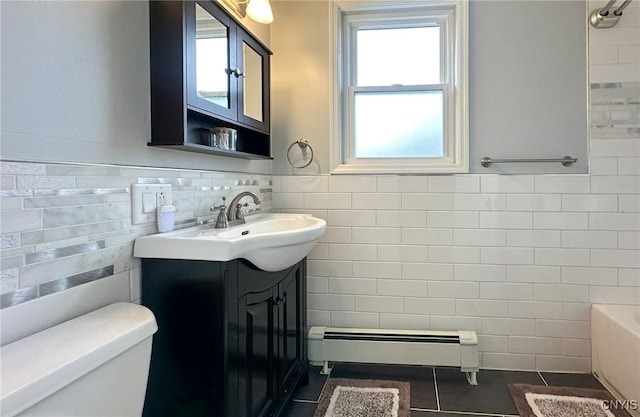 bathroom with tile walls, tile patterned flooring, a healthy amount of sunlight, and baseboard heating