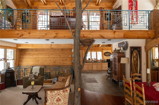 living room featuring a high ceiling, sink, and wooden walls