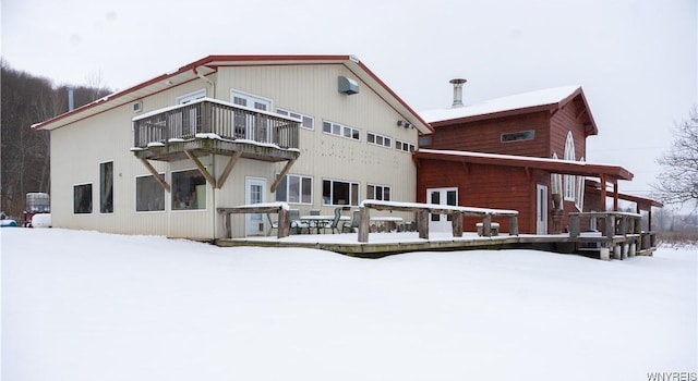 snow covered back of property featuring a balcony