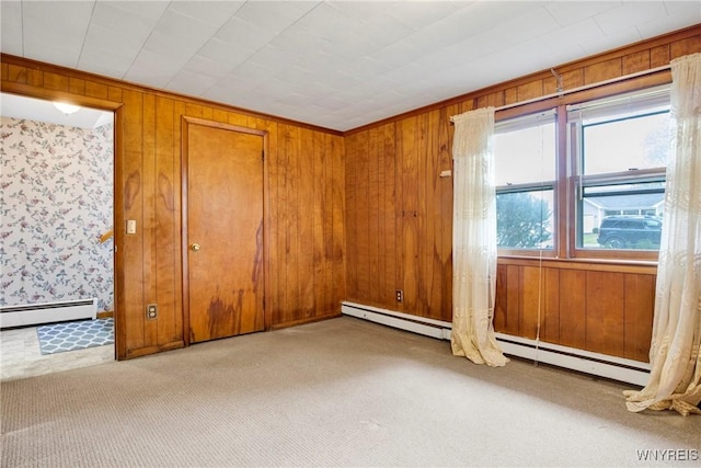 carpeted empty room featuring a baseboard radiator and wooden walls