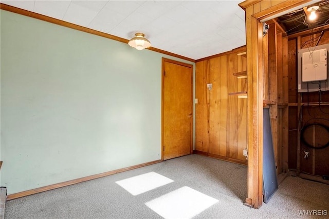 carpeted spare room featuring crown molding and wood walls