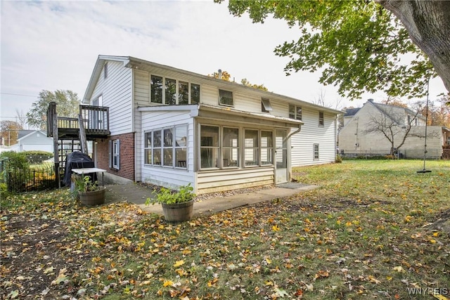 back of property featuring a lawn, a sunroom, and a deck