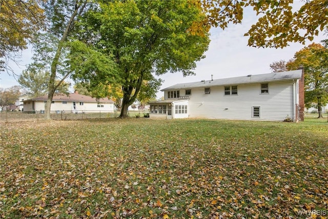 back of house featuring a yard and a sunroom