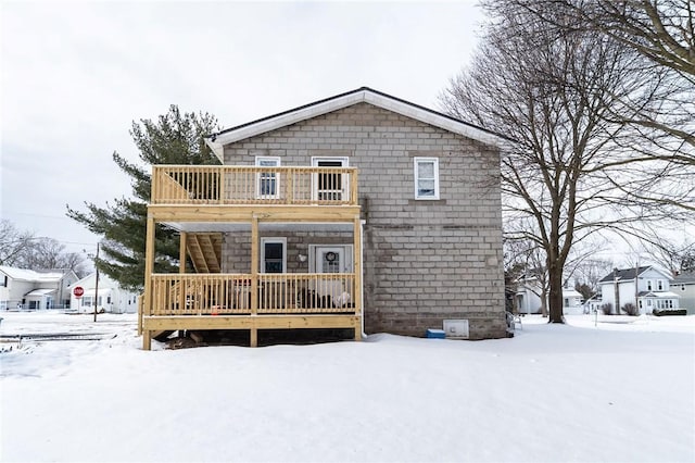 snow covered back of property featuring a wooden deck