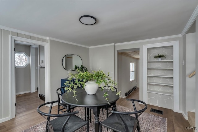 dining space featuring hardwood / wood-style floors, crown molding, and baseboard heating