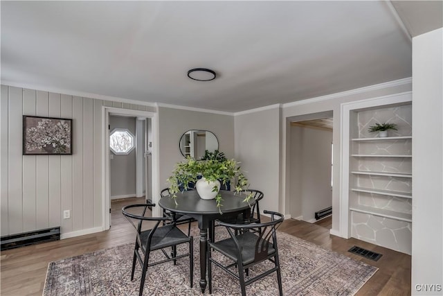 dining space featuring hardwood / wood-style flooring, a baseboard radiator, and ornamental molding