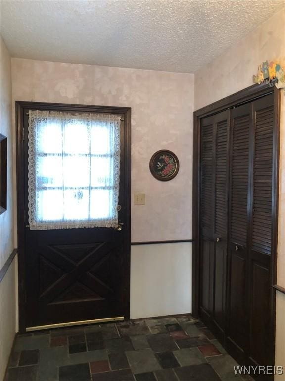 foyer featuring stone finish floor and a textured ceiling