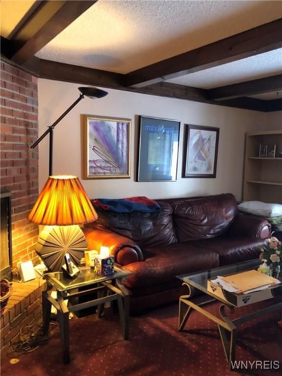 carpeted living room featuring beam ceiling and a textured ceiling