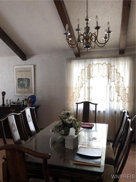 dining area featuring an inviting chandelier, beam ceiling, a textured ceiling, and a wealth of natural light