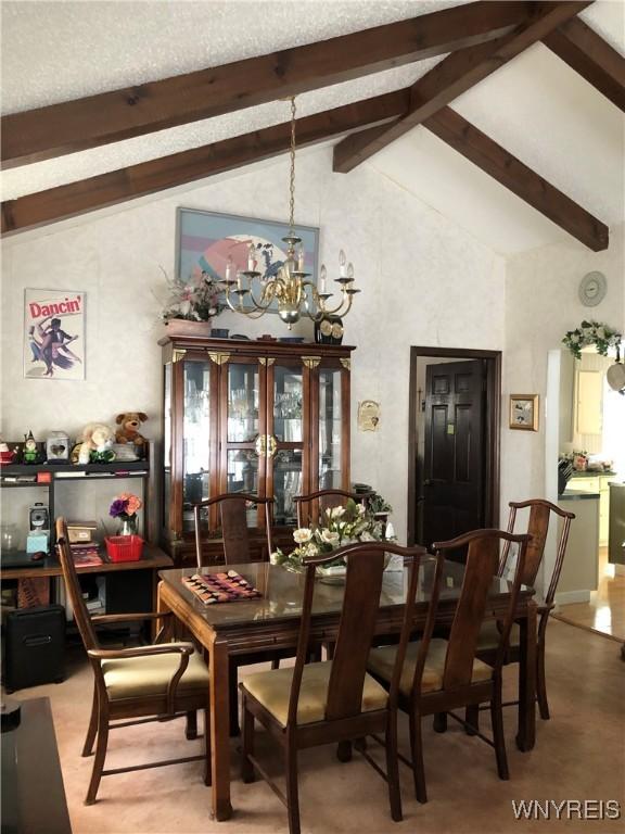 dining space with beam ceiling, high vaulted ceiling, and an inviting chandelier