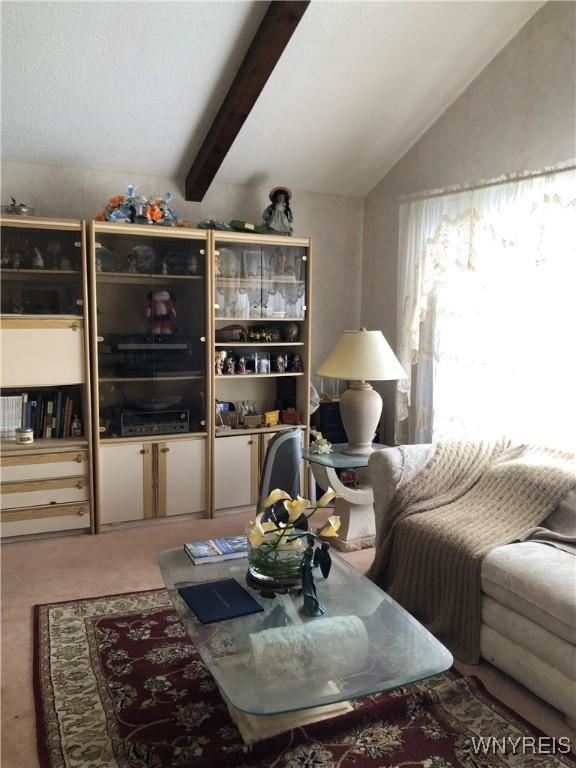 carpeted living room featuring vaulted ceiling with beams