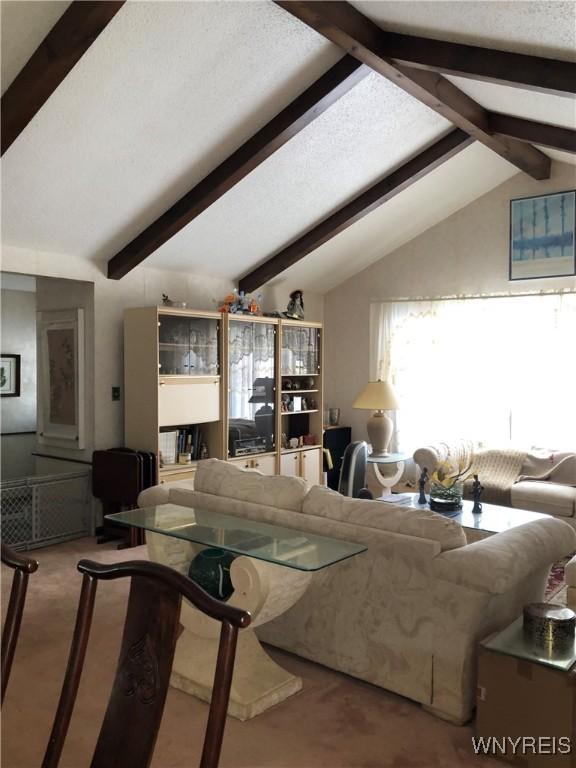 living room with vaulted ceiling with beams, a textured ceiling, and carpet flooring