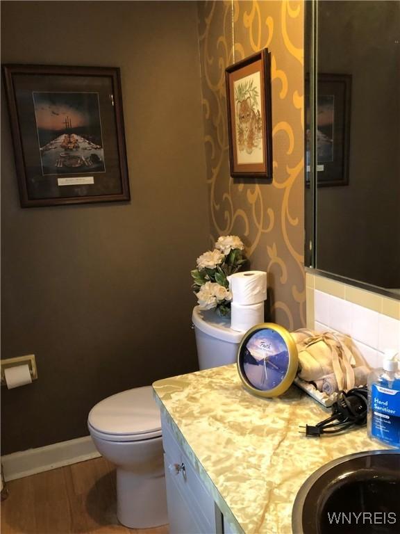 bathroom with vanity, hardwood / wood-style floors, decorative backsplash, and toilet