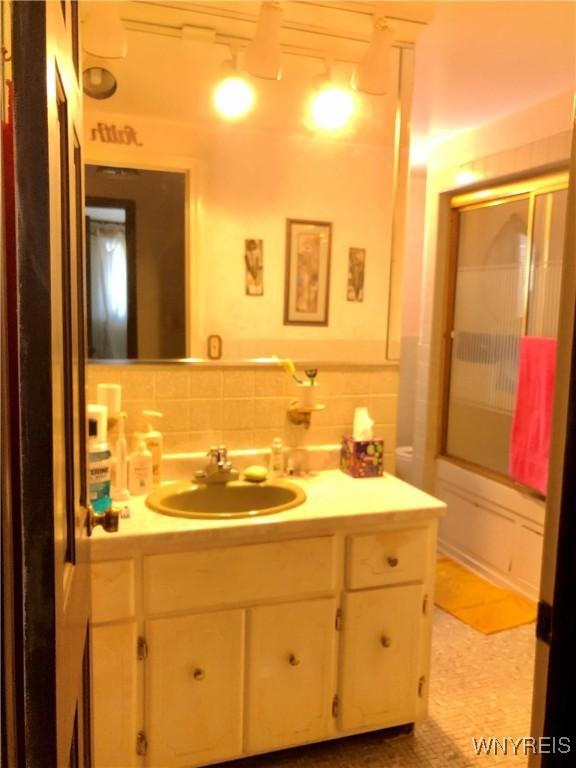 bathroom featuring vanity and tile walls