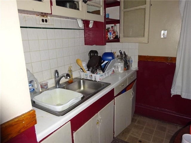 kitchen featuring dark tile patterned floors, sink, and backsplash