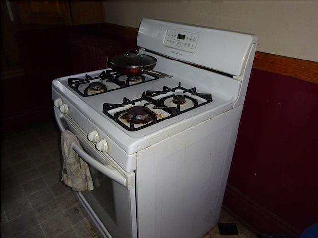 kitchen featuring white range with gas cooktop and dark tile patterned floors