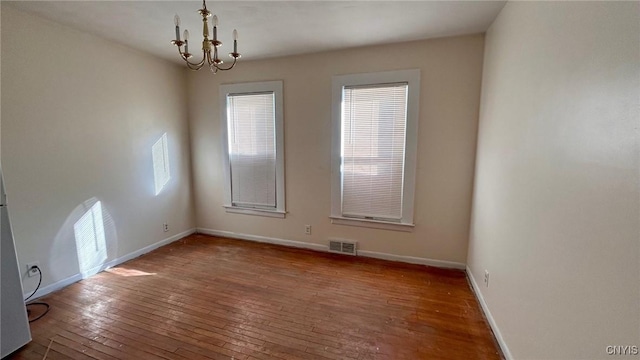 empty room featuring hardwood / wood-style floors and a notable chandelier