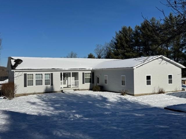 snow covered back of property featuring a porch