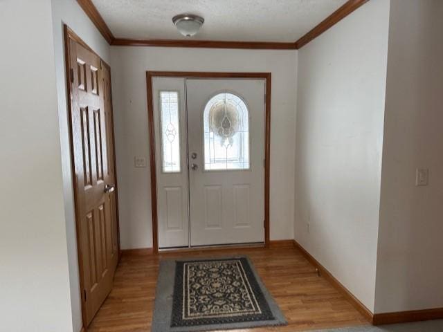 doorway to outside featuring ornamental molding, light hardwood / wood-style flooring, and a textured ceiling