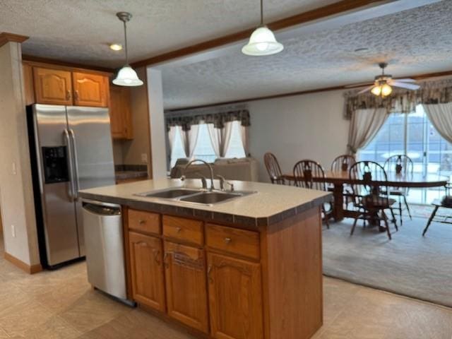 kitchen featuring pendant lighting, stainless steel appliances, sink, and a center island with sink