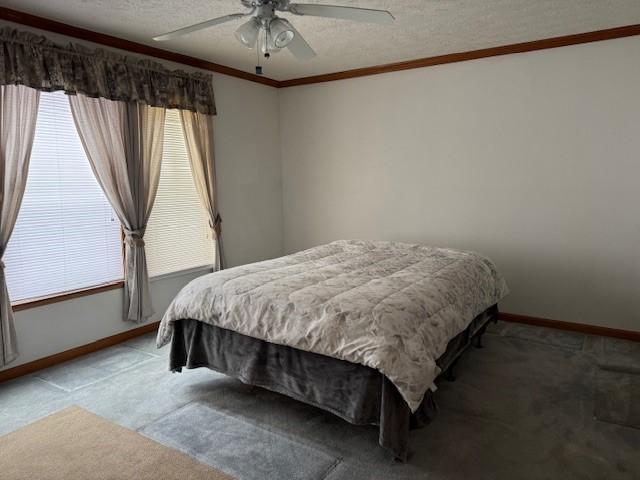 carpeted bedroom featuring ceiling fan, ornamental molding, and a textured ceiling