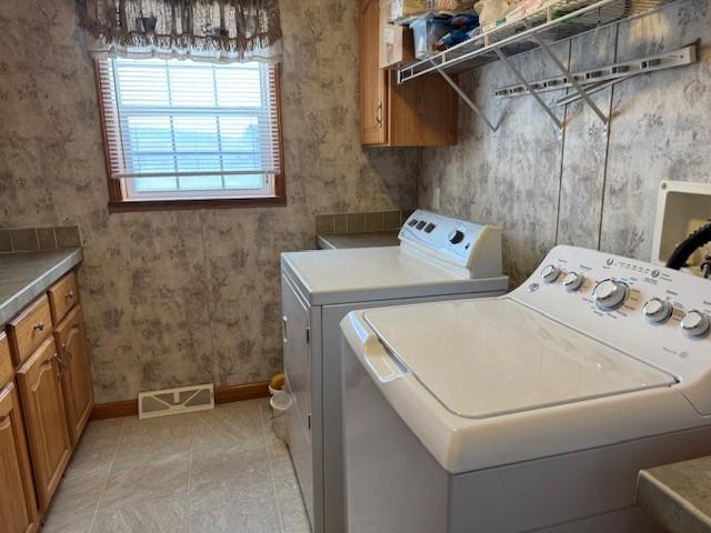 clothes washing area featuring cabinets, separate washer and dryer, and light tile patterned floors