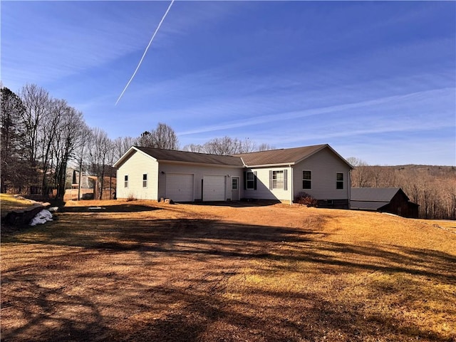 rear view of property featuring driveway and a garage