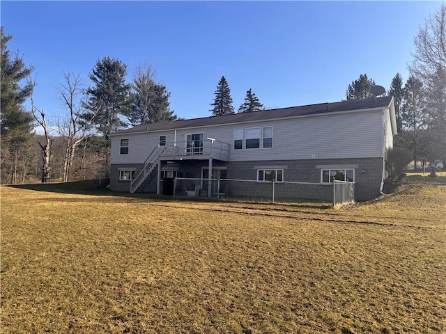 rear view of house with a deck, stairway, a lawn, and fence