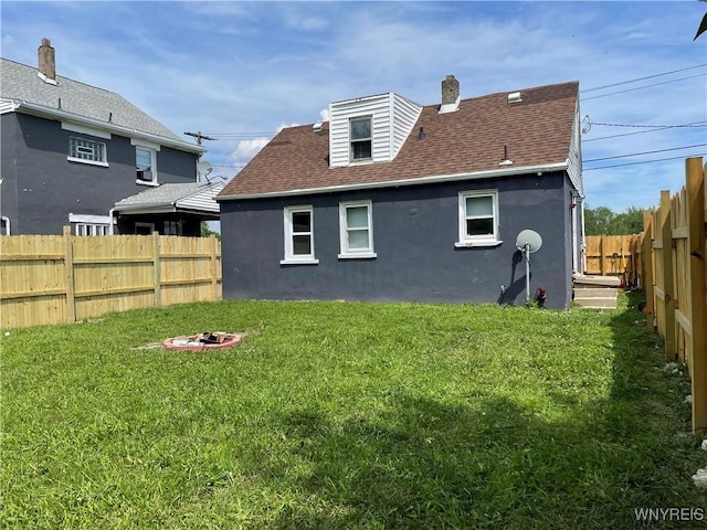 back of house featuring a lawn and an outdoor fire pit