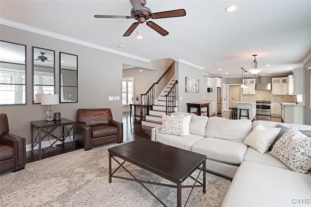 living room featuring sink, light hardwood / wood-style flooring, ornamental molding, and ceiling fan