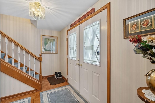 entryway with parquet floors, a notable chandelier, and french doors