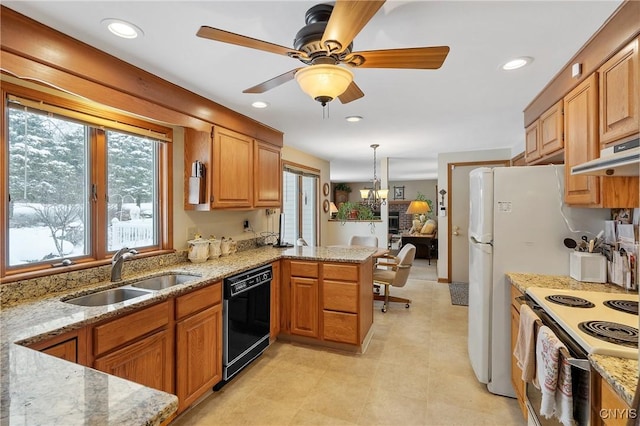 kitchen with hanging light fixtures, light stone countertops, black dishwasher, and sink