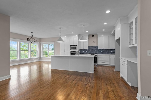 kitchen featuring white cabinetry, stainless steel appliances, a center island with sink, and pendant lighting