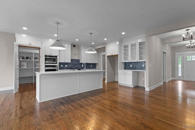 kitchen featuring stainless steel appliances, pendant lighting, a center island with sink, and white cabinets