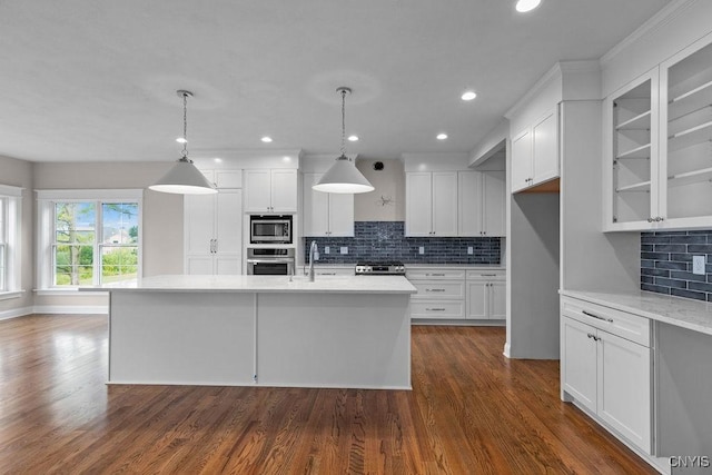 kitchen featuring hanging light fixtures, an island with sink, appliances with stainless steel finishes, and white cabinets