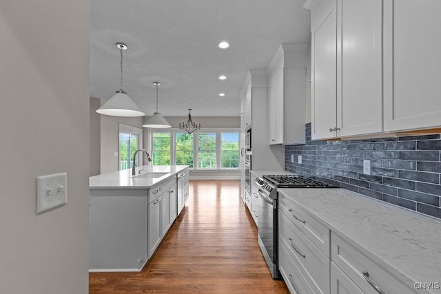 kitchen featuring white cabinetry, sink, decorative light fixtures, and stainless steel appliances