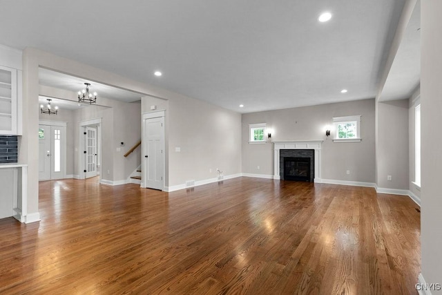 unfurnished living room with hardwood / wood-style flooring and a notable chandelier