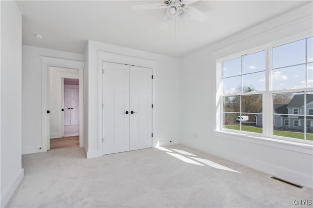 unfurnished bedroom featuring ceiling fan, a closet, and light carpet