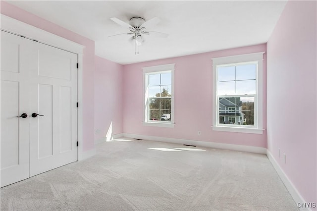 unfurnished room featuring plenty of natural light, light colored carpet, and ceiling fan