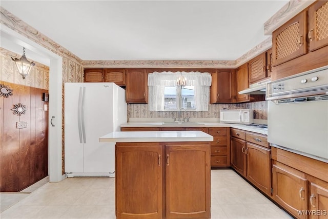 kitchen featuring an inviting chandelier, white appliances, sink, and a kitchen island