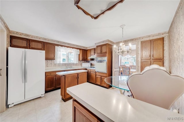 kitchen with sink, white appliances, an inviting chandelier, tasteful backsplash, and decorative light fixtures