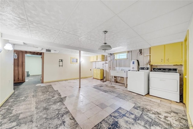 basement featuring washing machine and clothes dryer, sink, and a drop ceiling