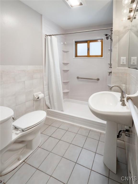 bathroom featuring tile walls, tile patterned flooring, toilet, and walk in shower