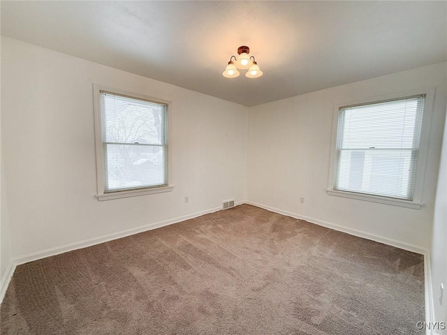 spare room featuring an inviting chandelier and carpet