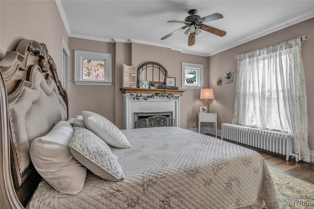 bedroom with ceiling fan, hardwood / wood-style floors, radiator heating unit, a fireplace, and ornamental molding